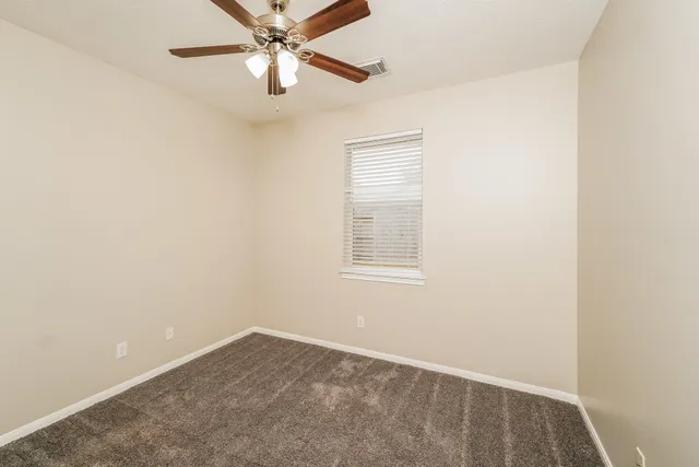 an empty room with a window and a fan