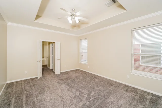 an empty room with a chandelier fan and windows