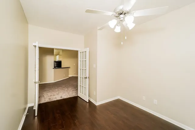an empty room with wooden floor and fan
