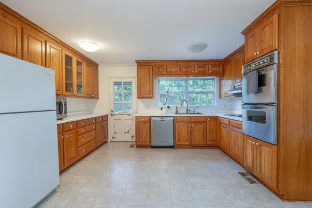 a large kitchen with stainless steel appliances granite countertop a refrigerator a sink dishwasher a oven with wooden cabinets and floor