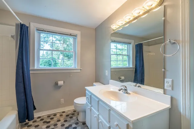 a bathroom with a sink a toilet a mirror and a window