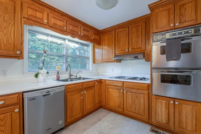 a kitchen with stainless steel appliances granite countertop a sink a stove and cabinets