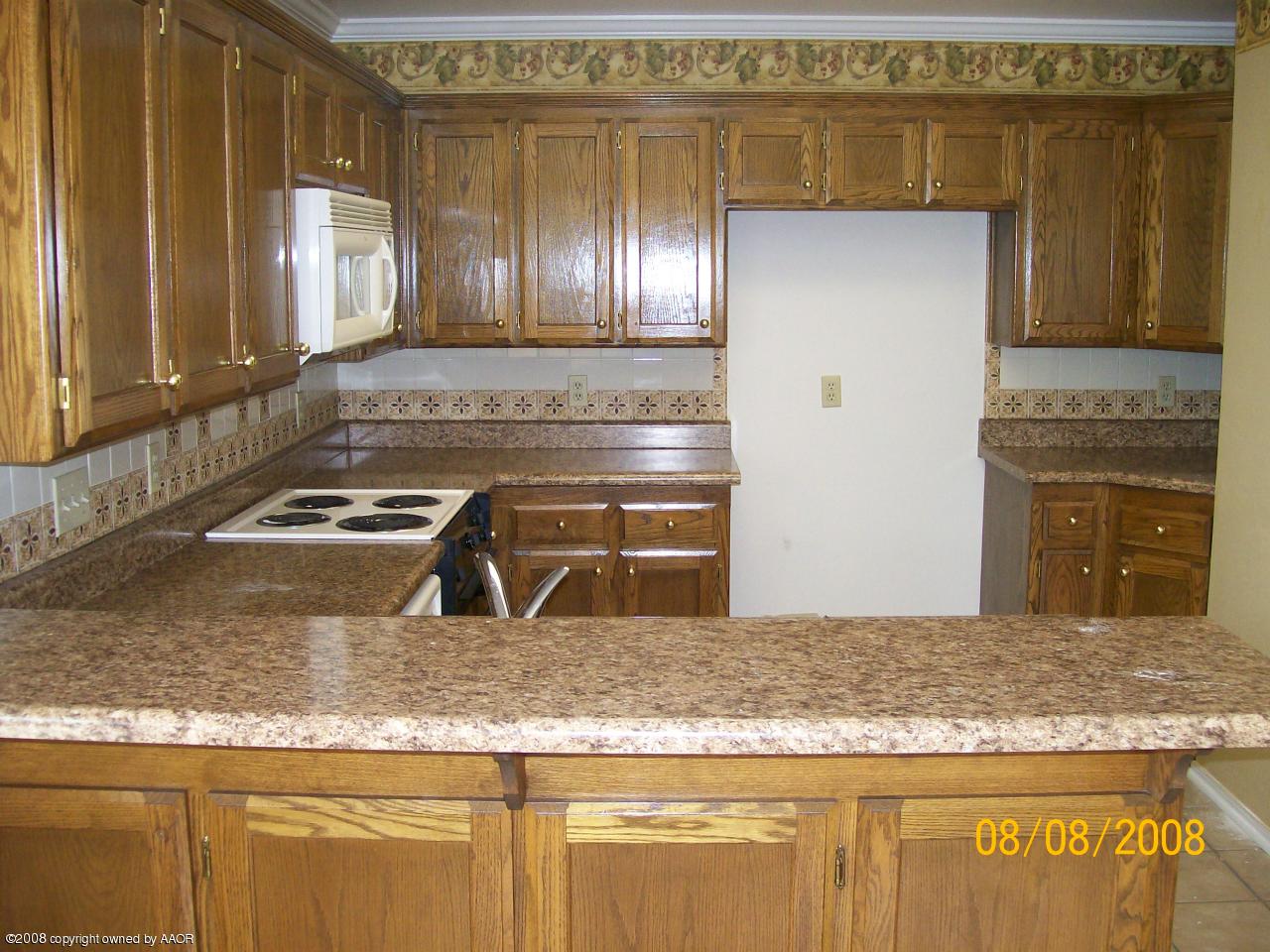 8008 Claret Street Amarillo, TX 79110 - Photo 5 of 9 a kitchen with granite countertop a sink a stove and cabinets