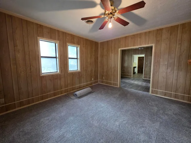 an empty room with chandelier fan and windows