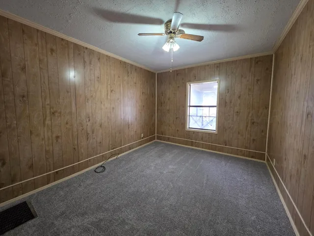an empty room with windows and fan