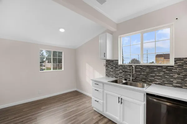 a kitchen with stainless steel appliances granite countertop a stove a sink and white cabinets with wooden floor