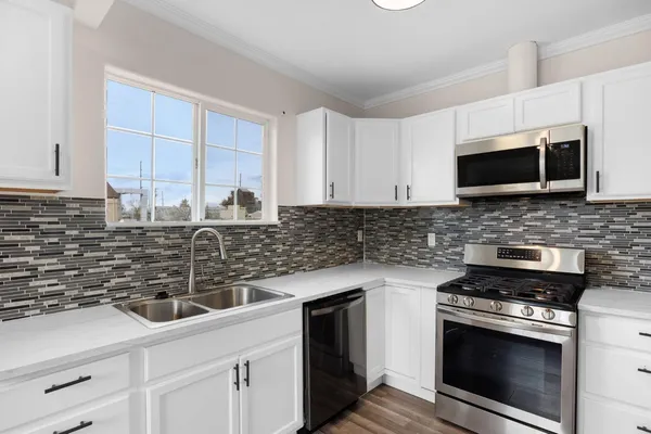 a kitchen with stainless steel appliances white cabinets and a stove top oven
