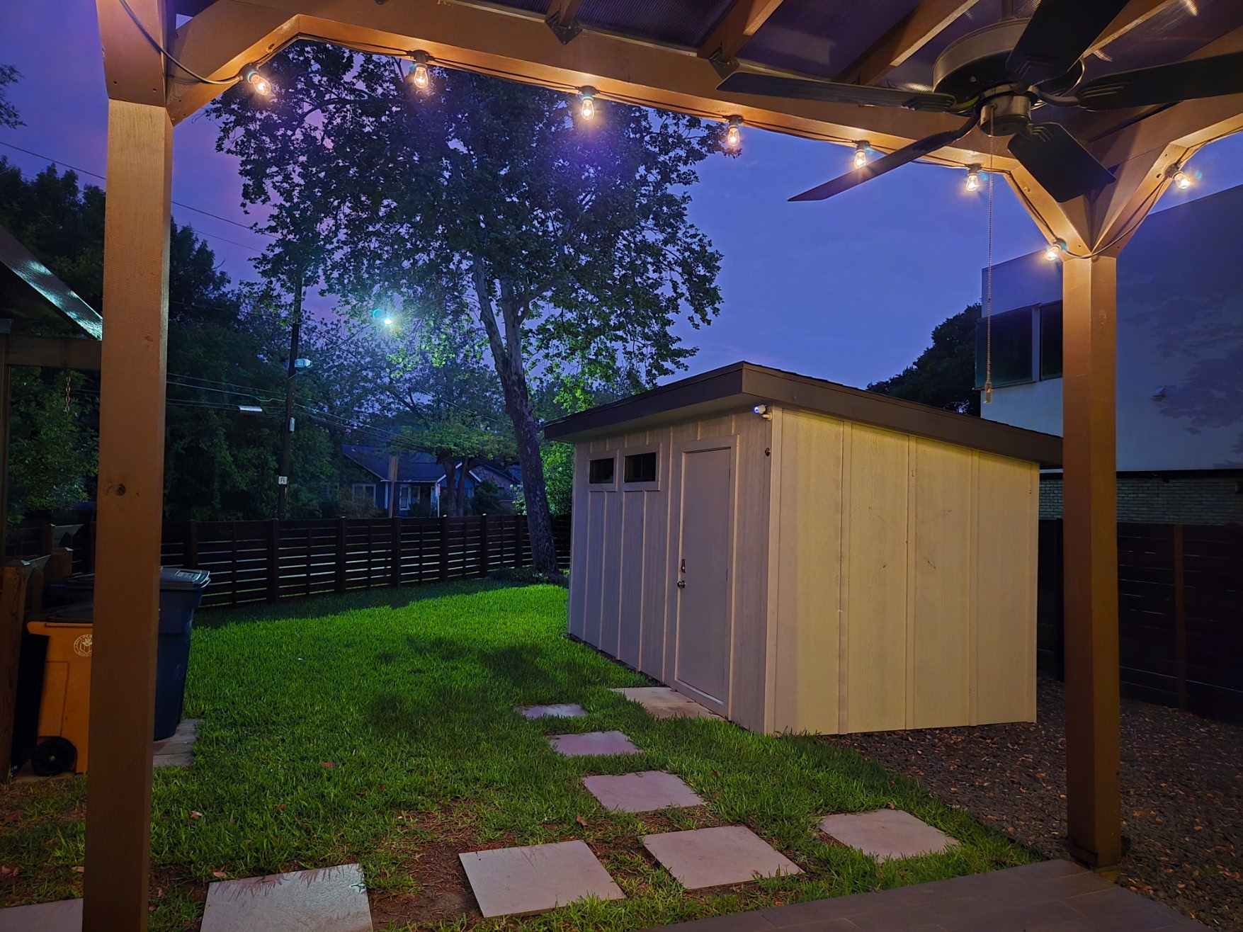 2103 Kinney Avenue Austin, TX 78704 - Photo 14 of 40 Spacious yard with a lawn, a detached shed, a privacy fence, and string lights illuminating a covered patio area