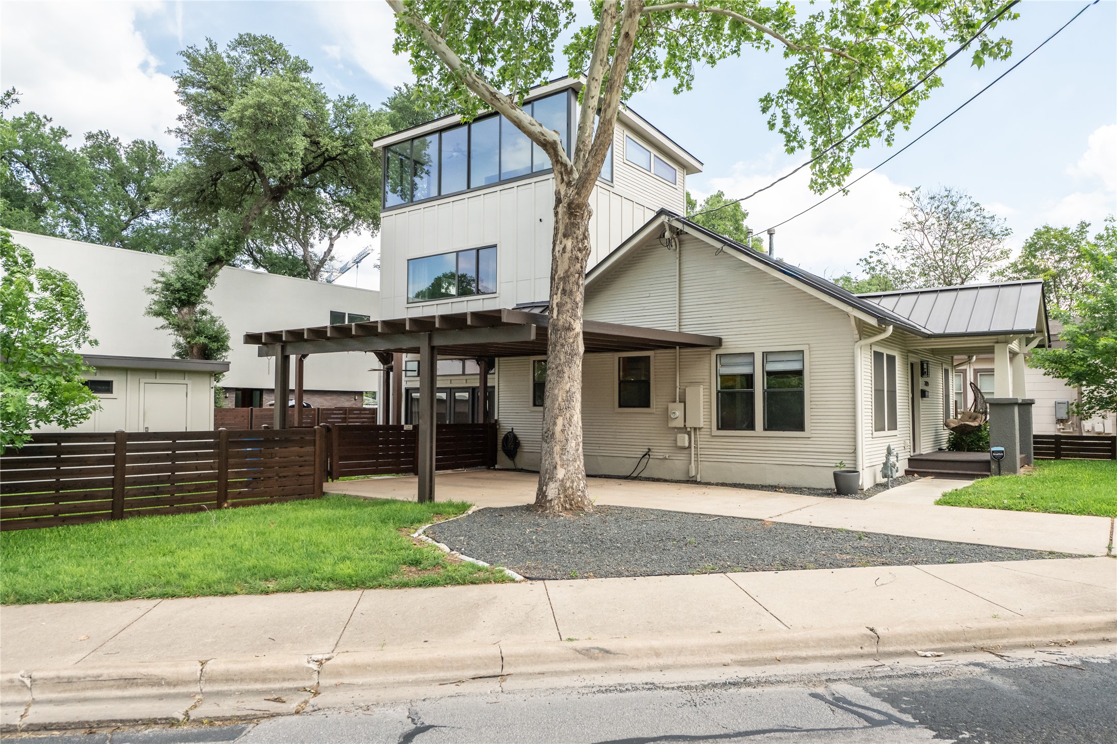 2103 Kinney Avenue Austin, TX 78704 - Photo 2 of 40 The property features a multi-level design with a prominent third-story window feature, a covered patio area with a wooden pergola, and a dark metal roof