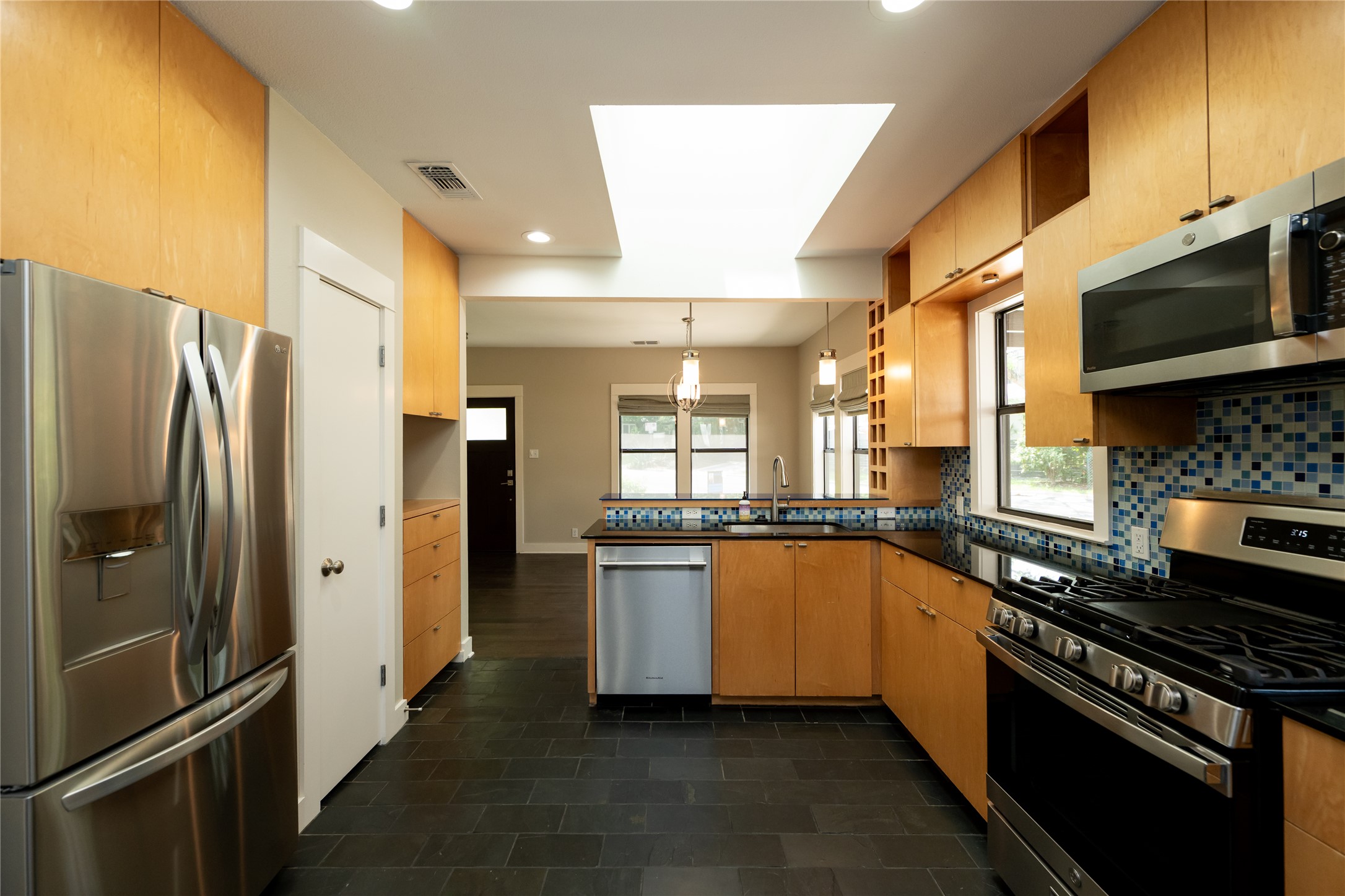 2103 Kinney Avenue Austin, TX 78704 - Photo 21 of 40 The kitchen features stainless steel appliances, light wood cabinetry, black countertops, and a tiled backsplash