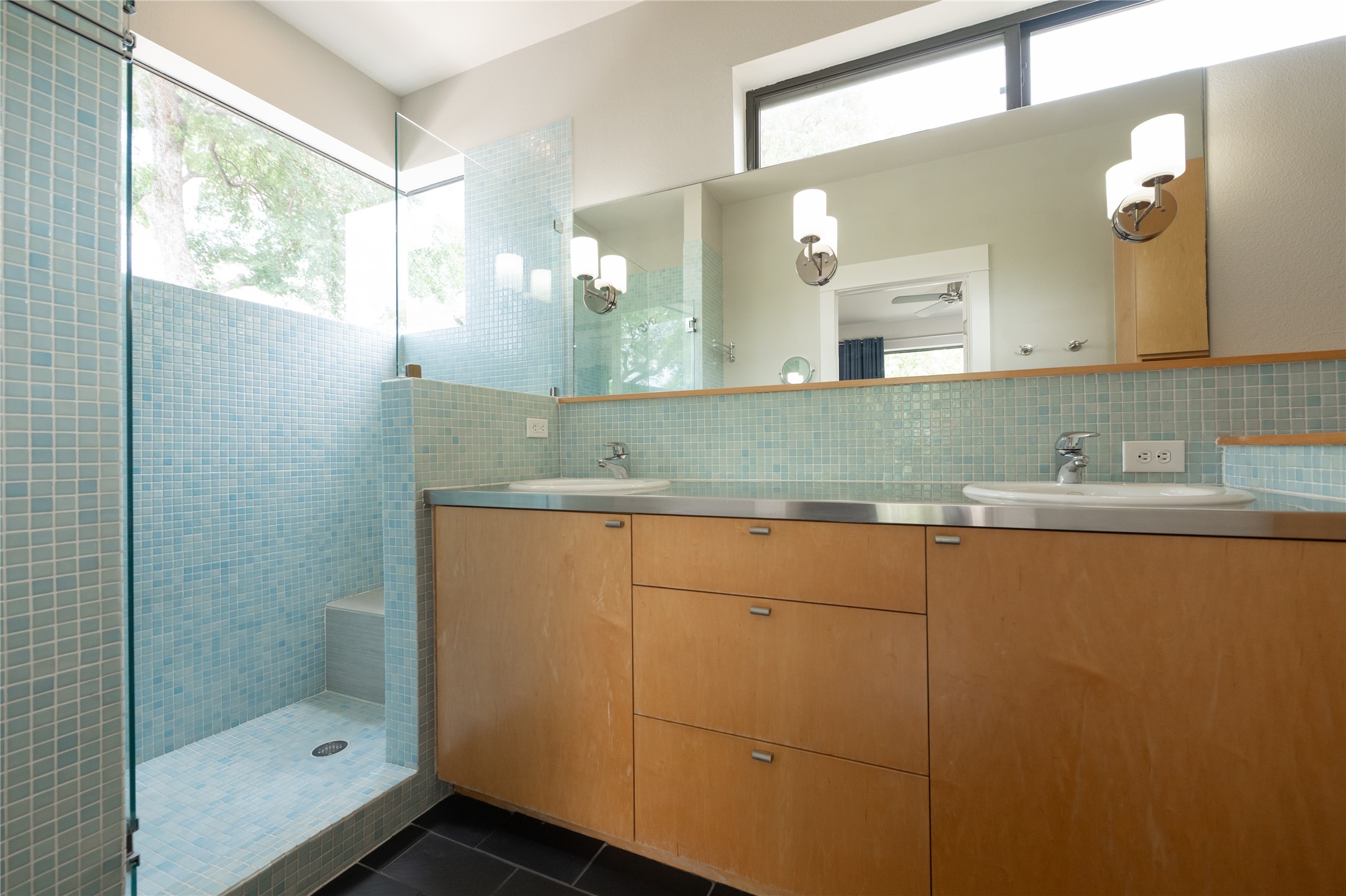 2103 Kinney Avenue Austin, TX 78704 - Photo 28 of 40 Primary bathroom featuring dual sinks with individual wall-mounted sconces, a large mirror, and wood cabinetry