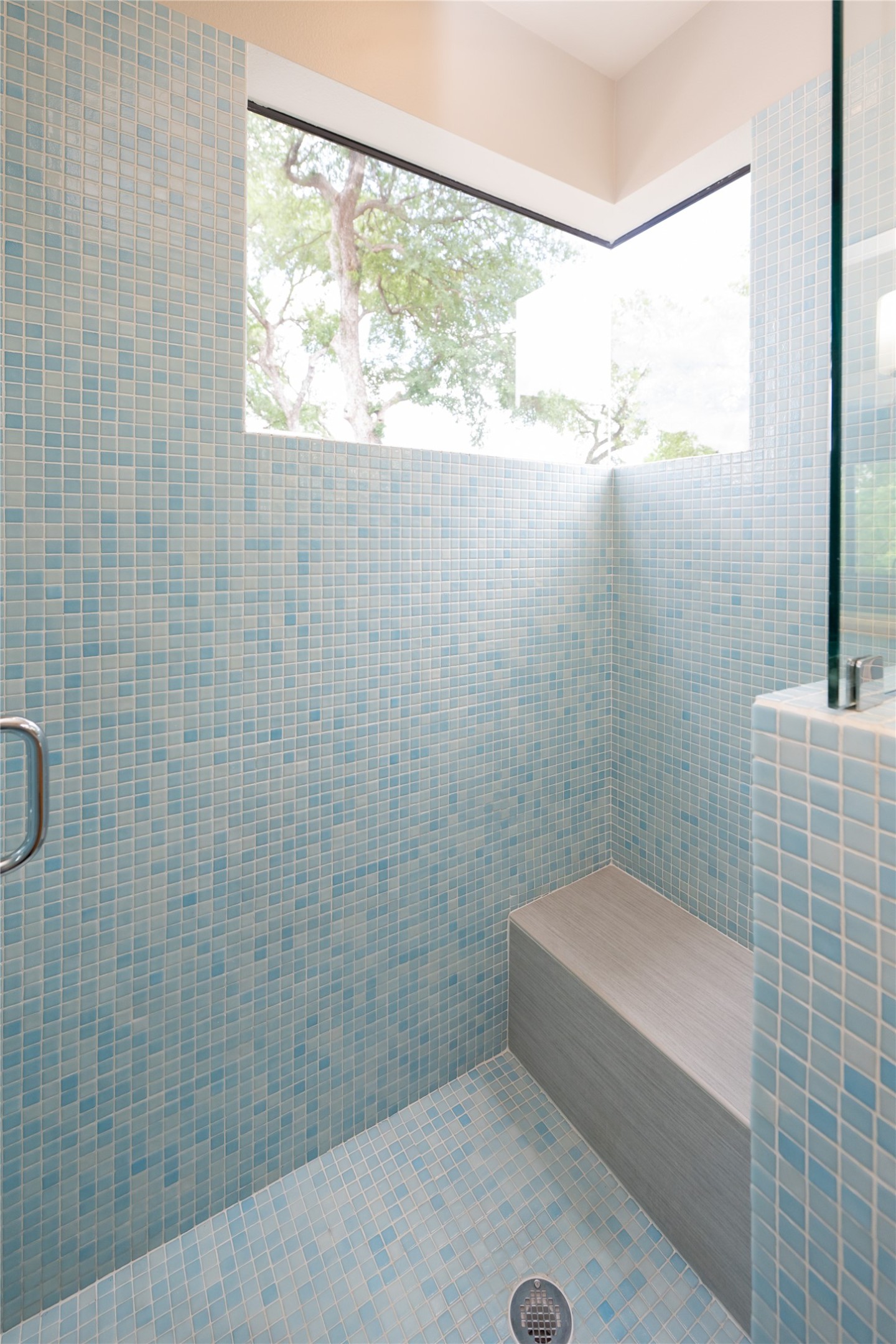 2103 Kinney Avenue Austin, TX 78704 - Photo 29 of 40 Primary shower featuring light blue mosaic tiling, a built-in bench, and a large window