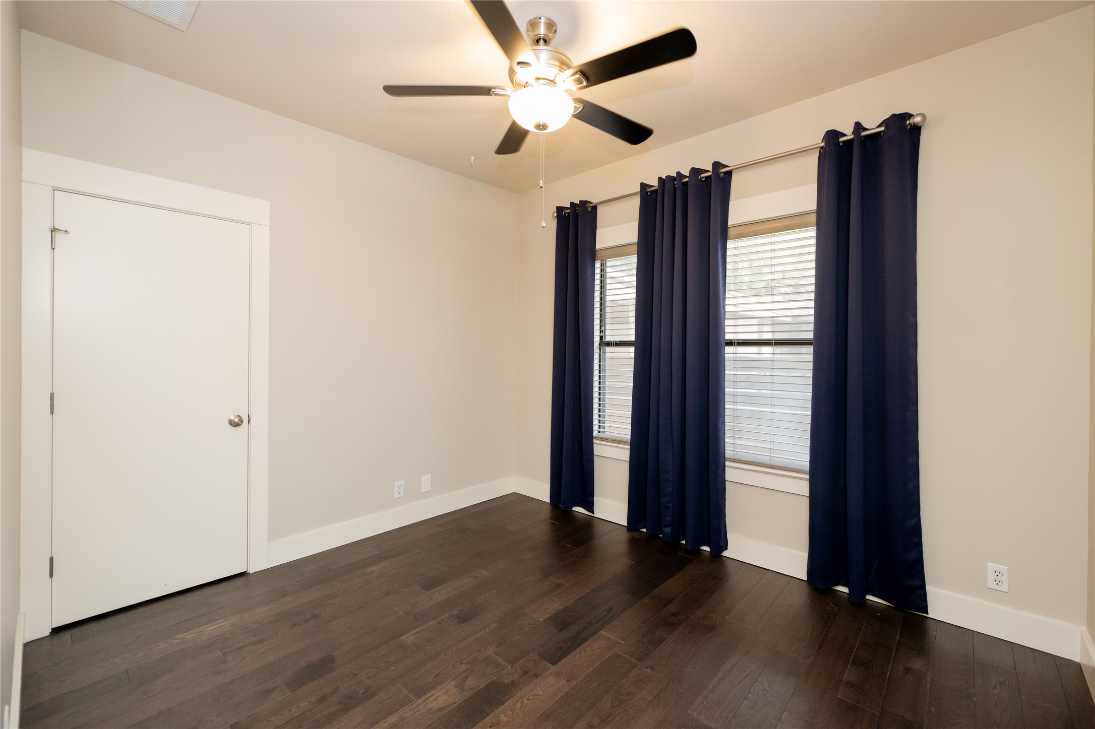 2103 Kinney Avenue Austin, TX 78704 - Photo 31 of 40 This room features dark wood flooring, light-colored walls, and a ceiling fan with integrated lighting