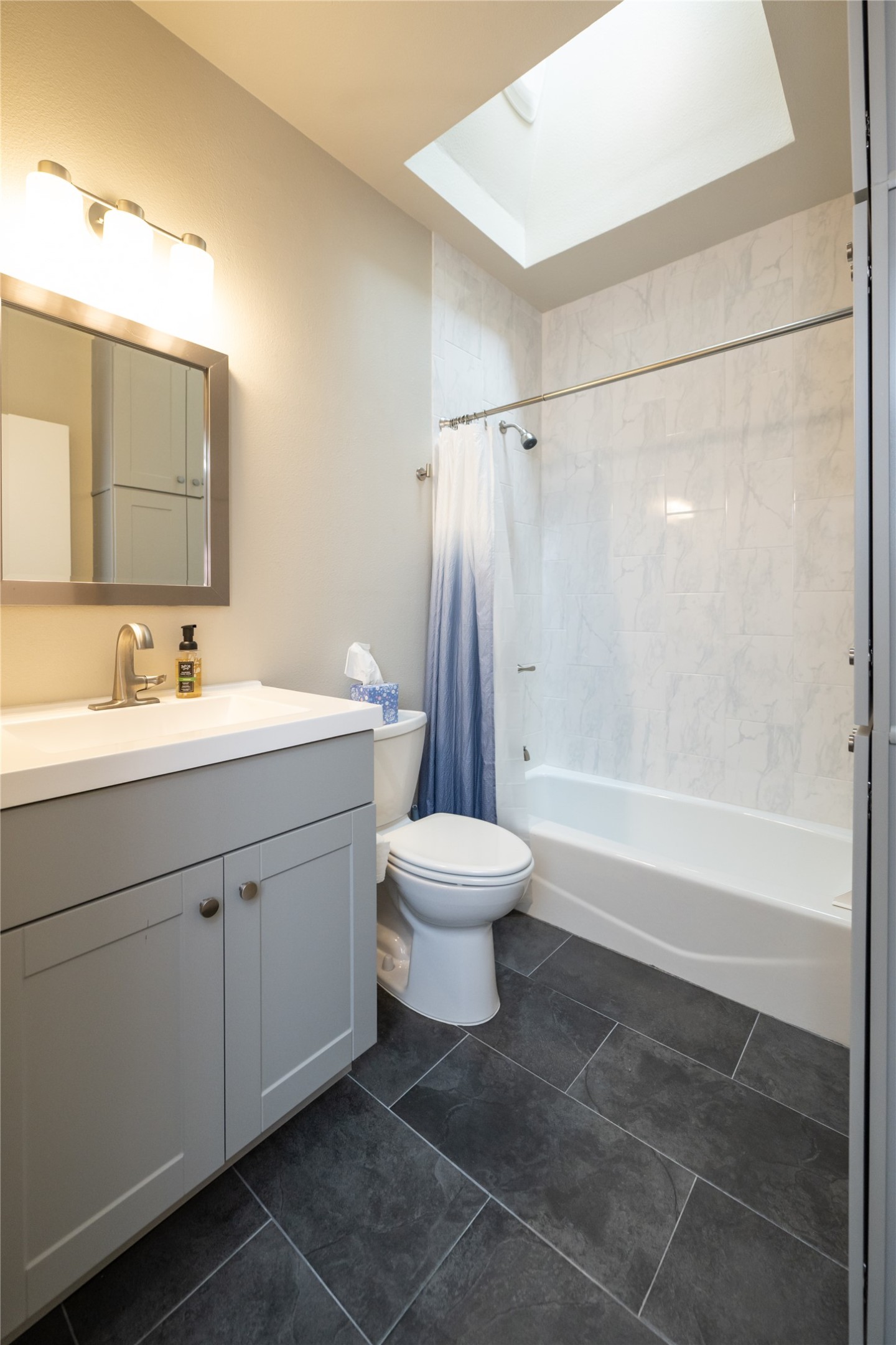 2103 Kinney Avenue Austin, TX 78704 - Photo 32 of 40 Bathroom featuring a vanity with a light gray cabinet and white countertop, a toilet, a bathtub with a white tiled shower surround, and dark gray floor tiles