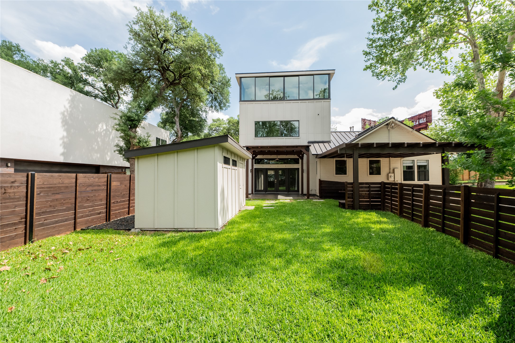 2103 Kinney Avenue Austin, TX 78704 - Photo 7 of 40 Featuring an extensive lawn area, a modern style shed, and a covered patio with a dark wood pergola