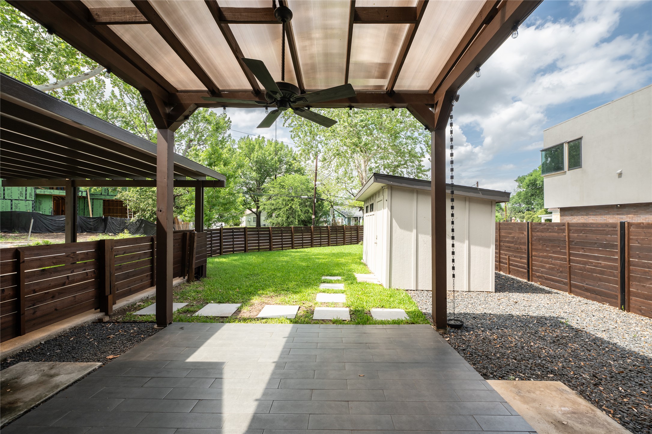 2103 Kinney Avenue Austin, TX 78704 - Photo 9 of 40 Outdoor patio featuring a pergola, ceiling fan, a misting system, a detached shed, and a grassy lawn with stepping stones