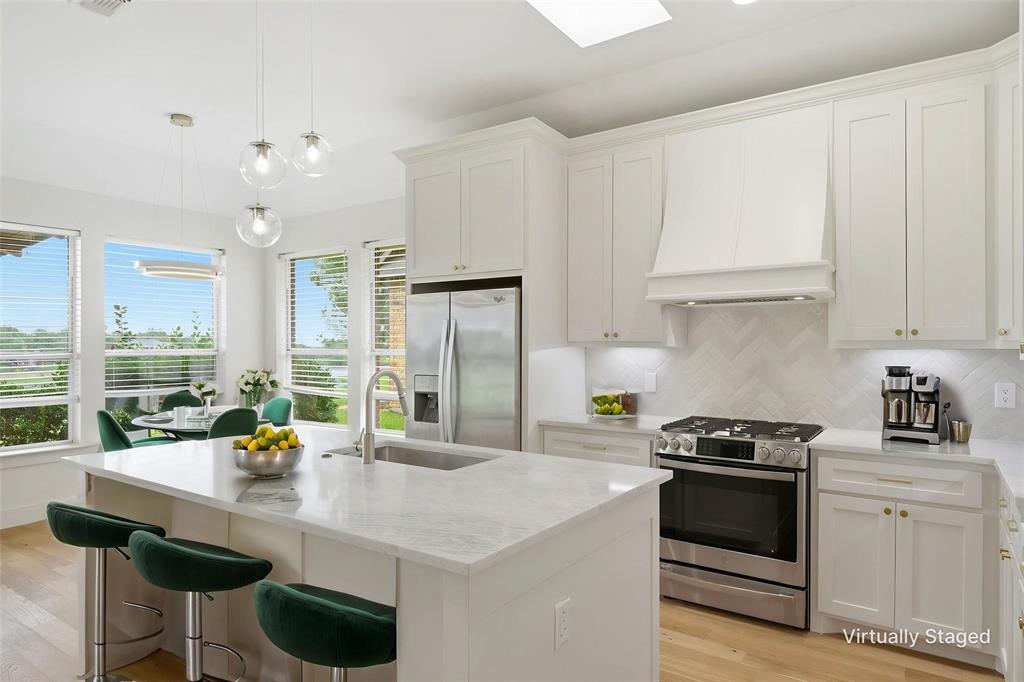 2104 Old McGarrah Road McKinney, TX 75072 - Photo 26 of 35 White shaker cabinetry with gold-tone hardware, stainless steel appliances, and a countertop island with an integrated sink