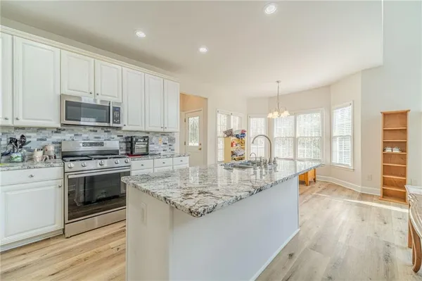 a kitchen with kitchen island granite countertop a sink and a stove top oven