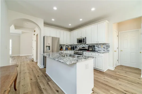 a kitchen with stainless steel appliances kitchen island granite countertop a stove refrigerator and cabinets