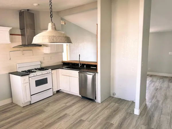 a kitchen with a stove and a wooden floor