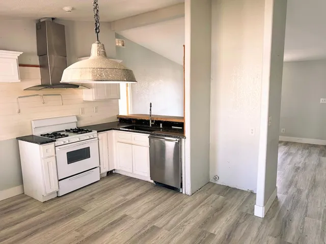 a kitchen with a stove and a wooden floor