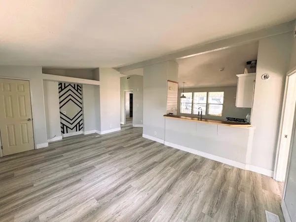 a view of a hallway with wooden floor and a living room