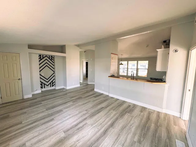a view of a hallway with wooden floor and a living room