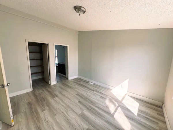a view of an empty room with wooden floor and closet