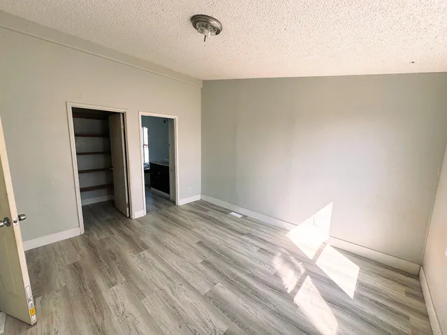 a view of an empty room with wooden floor and closet