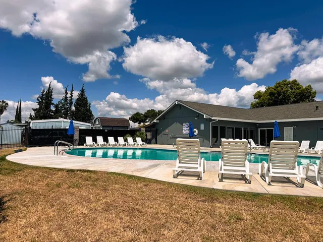 a view of a house with a big yard potted plants and a table