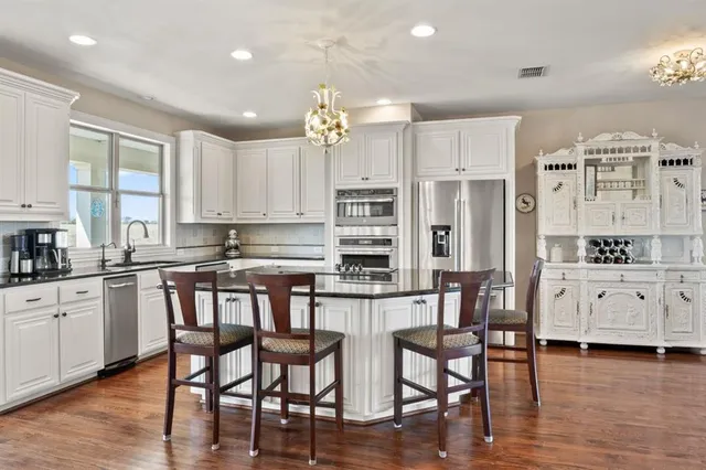 a kitchen with stainless steel appliances granite countertop a white cabinets and wooden floor