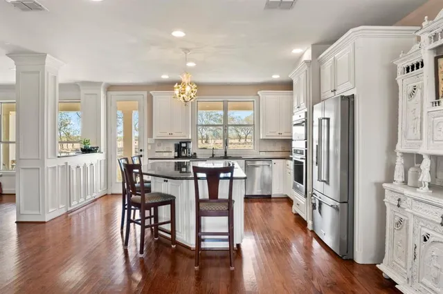 a kitchen with stainless steel appliances a dining table chairs refrigerator refrigerator and cabinets