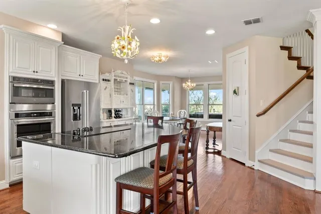 a kitchen with stainless steel appliances a refrigerator a stove top oven and a dining table with wooden floor