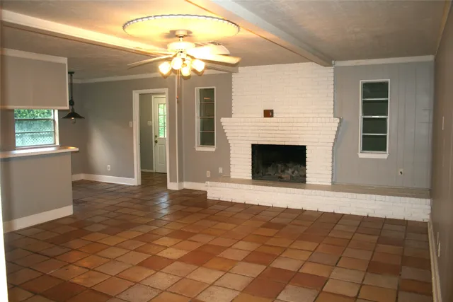 a view of an empty room with wooden floor and a fireplace