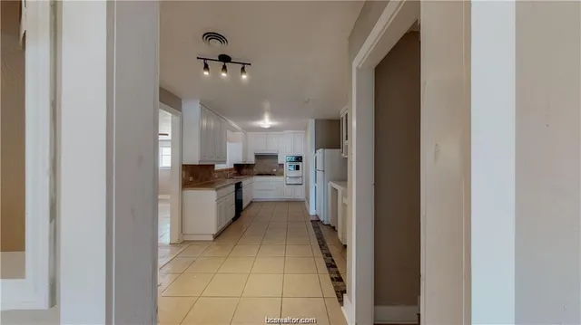 a kitchen with a refrigerator and white cabinets