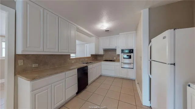 a kitchen with a refrigerator a oven and white cabinets