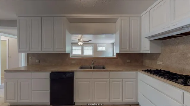 a kitchen with white cabinets and black appliances
