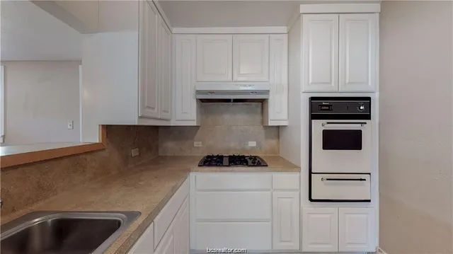 a kitchen with white cabinets and black appliances