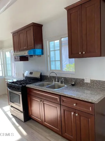 a kitchen with stainless steel appliances granite countertop a stove a sink dishwasher and cabinets with wooden floor