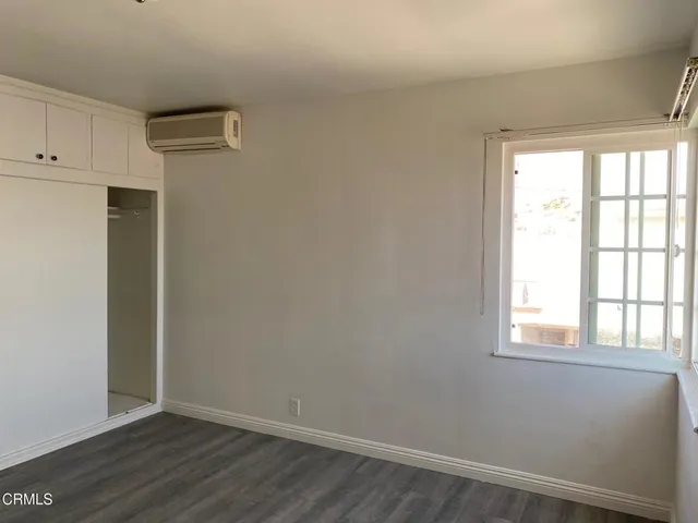 a view of an empty room with wooden floor and cabinet