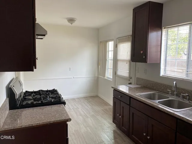 a kitchen with granite countertop a sink a stove and a wooden floor
