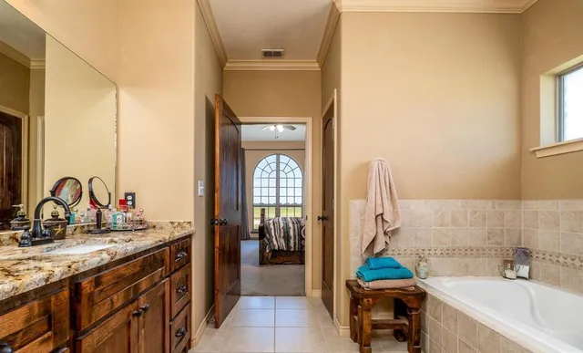 a en suite bathroom with a granite countertop tub sink a mirror and shower
