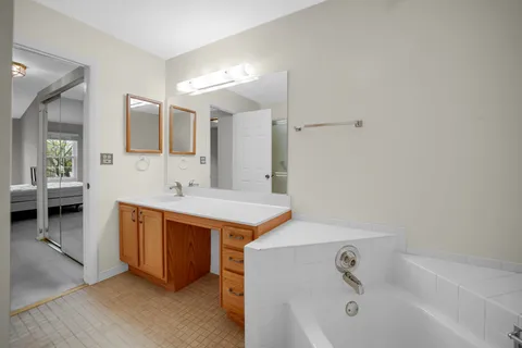 a spacious bathroom with a tub sink and mirror