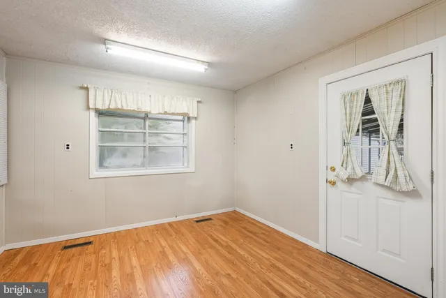 an empty room with wooden floor cabinet and windows
