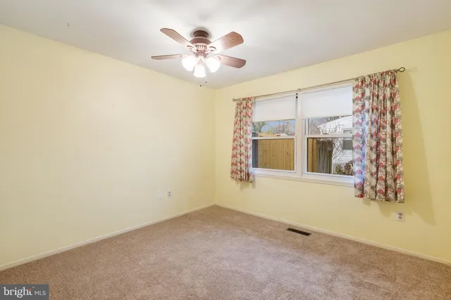 an empty room with a window and chandelier fan