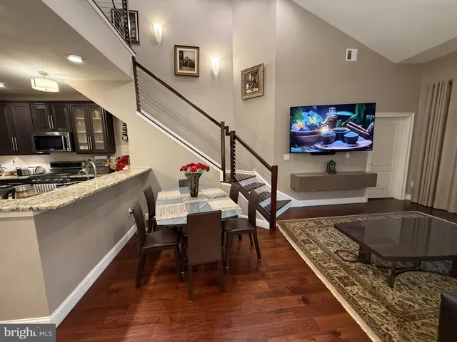 a kitchen with stainless steel appliances granite countertop a sink dishwasher a stove and a refrigerator with wooden floor