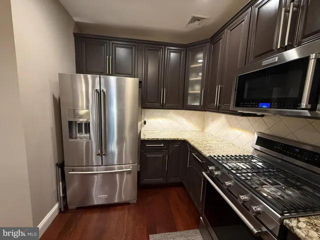 a kitchen with granite countertop a refrigerator and a stove top oven