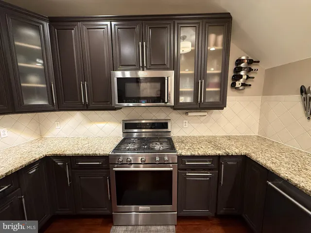 a kitchen with granite countertop cabinets stainless steel appliances and a counter space