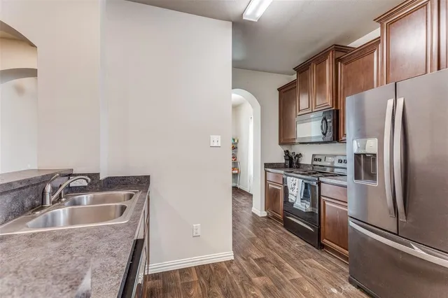 a kitchen with granite countertop a sink stove and refrigerator