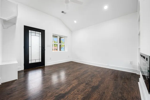 an empty room with wooden floor and windows